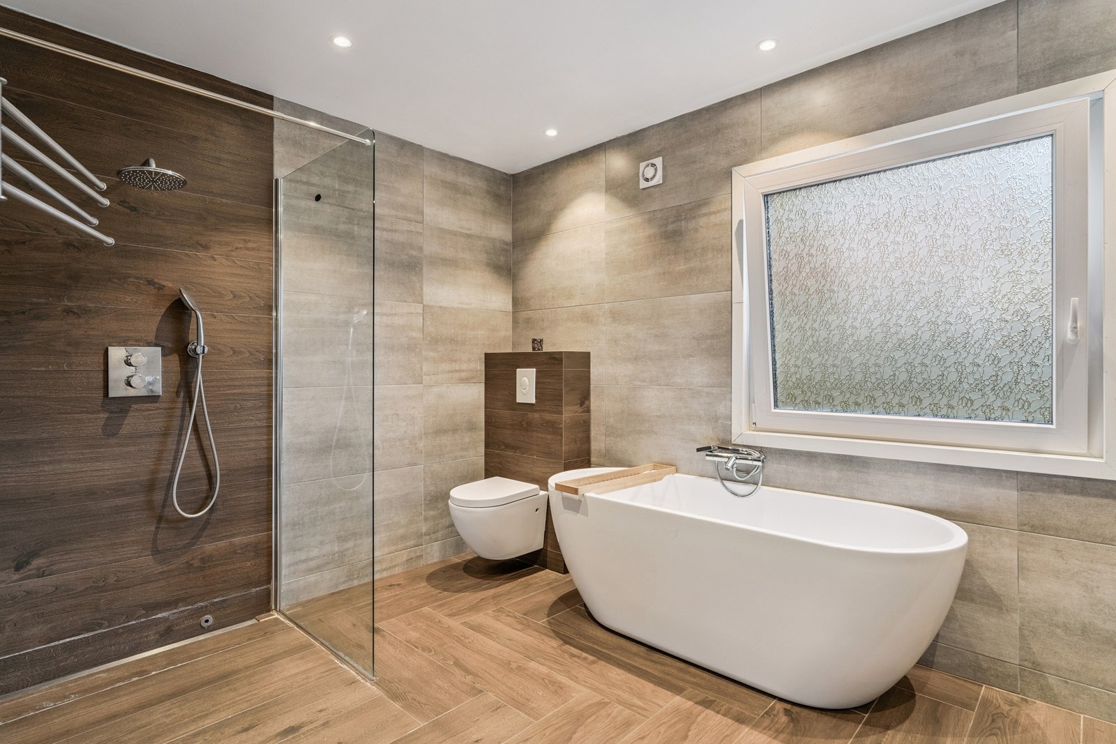 Rommet er innredet med flislagt baderomsmøbel med to servanter på, vegghengt toalett, badekar og dusjhjørne Galleribilde