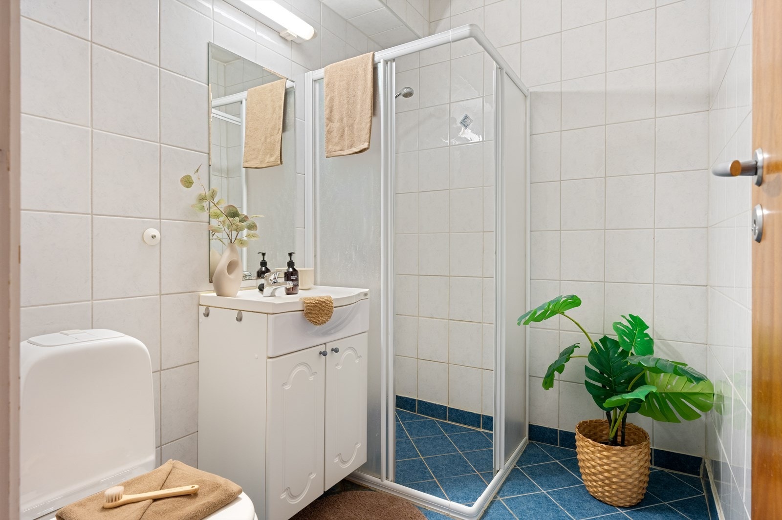 Lyst og helfliset bad med dusjhjørne og servant med oppbevaring. Galleribilde