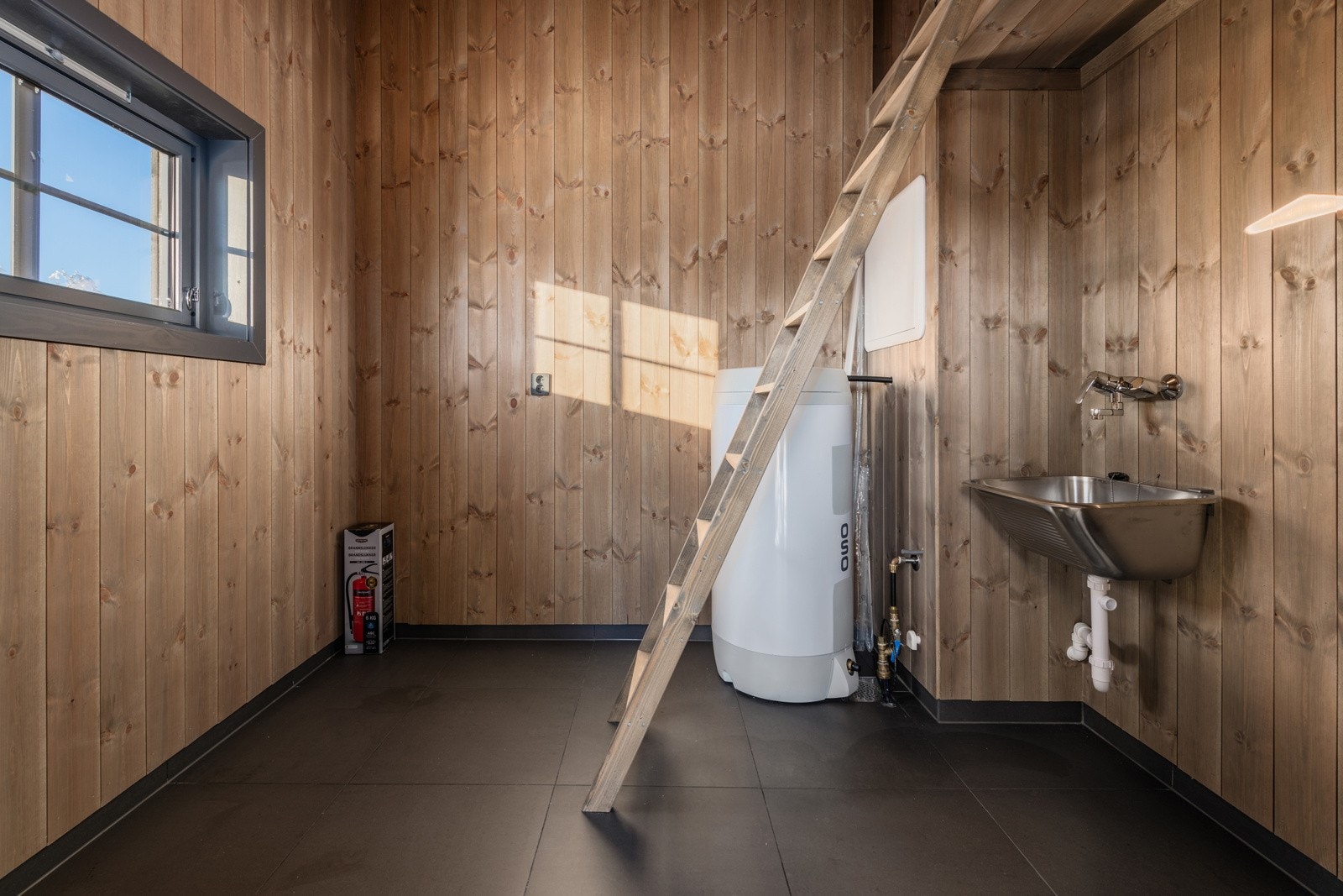 Hytta har et praktisk teknisk rom/vaskerom med opplegg for vaskemaskin og oppvaskkum i rustfritt stål. Her er det fliser på gulvet og gulvvarme. Galleribilde