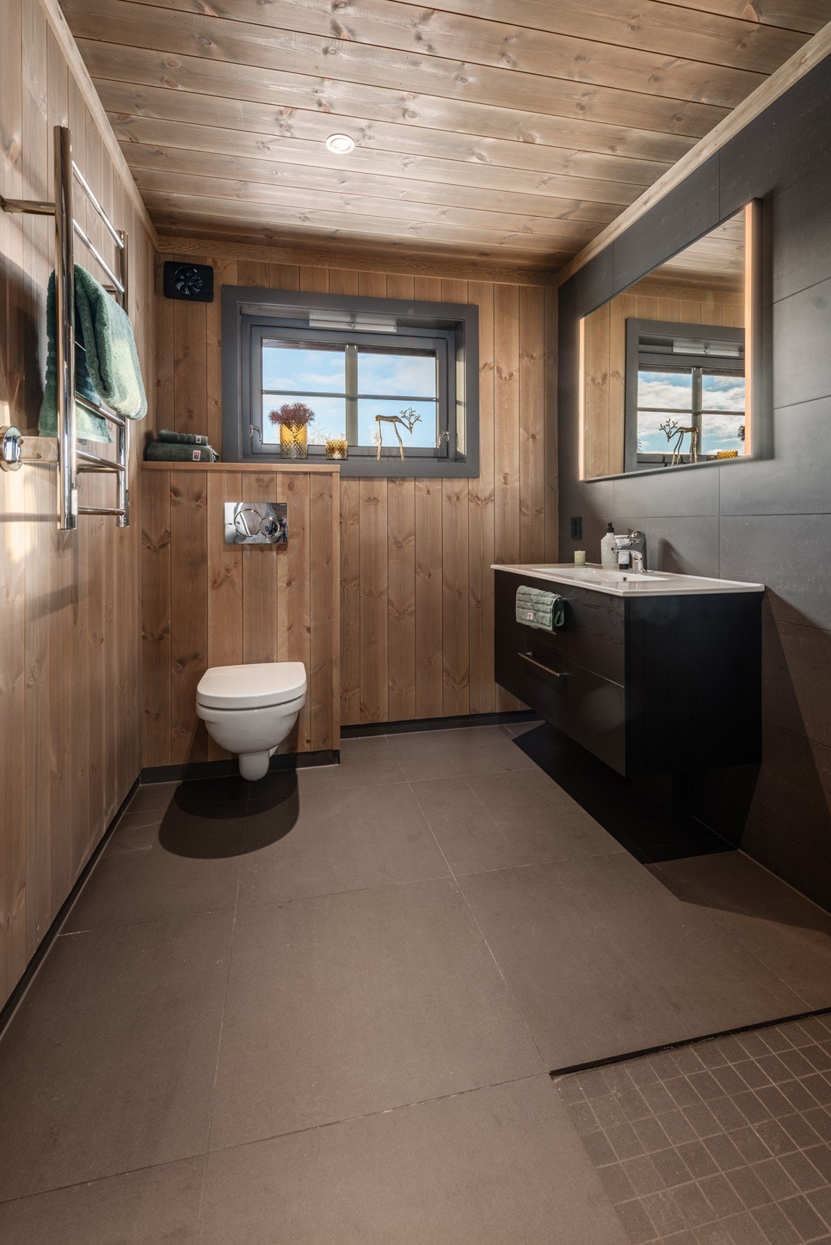 Badene er innredet med baderomsinnredning med servant, veggmontert toalett og dusjhjørne med innfellbare vegger. Galleribilde