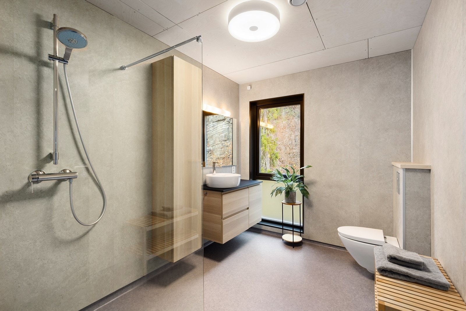 Badet i 2. etasje har vegghengt toalett og åpen dusjløsning avgrenset med dusjvegg i glass. Pen servantinnredning med tilhørende høyskap, samt speil og overlys. Galleribilde