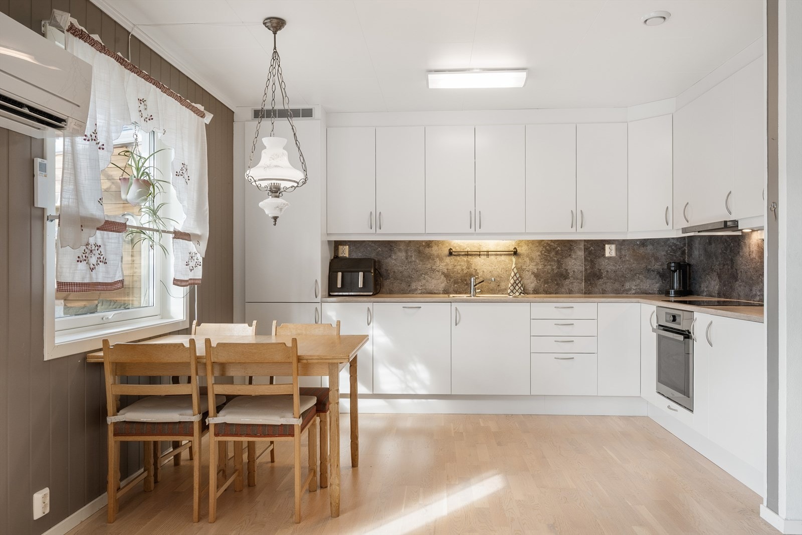 Kjøkkenet har en lys, tidløs innredning med slette fronter og benkeplate i laminat. Galleribilde