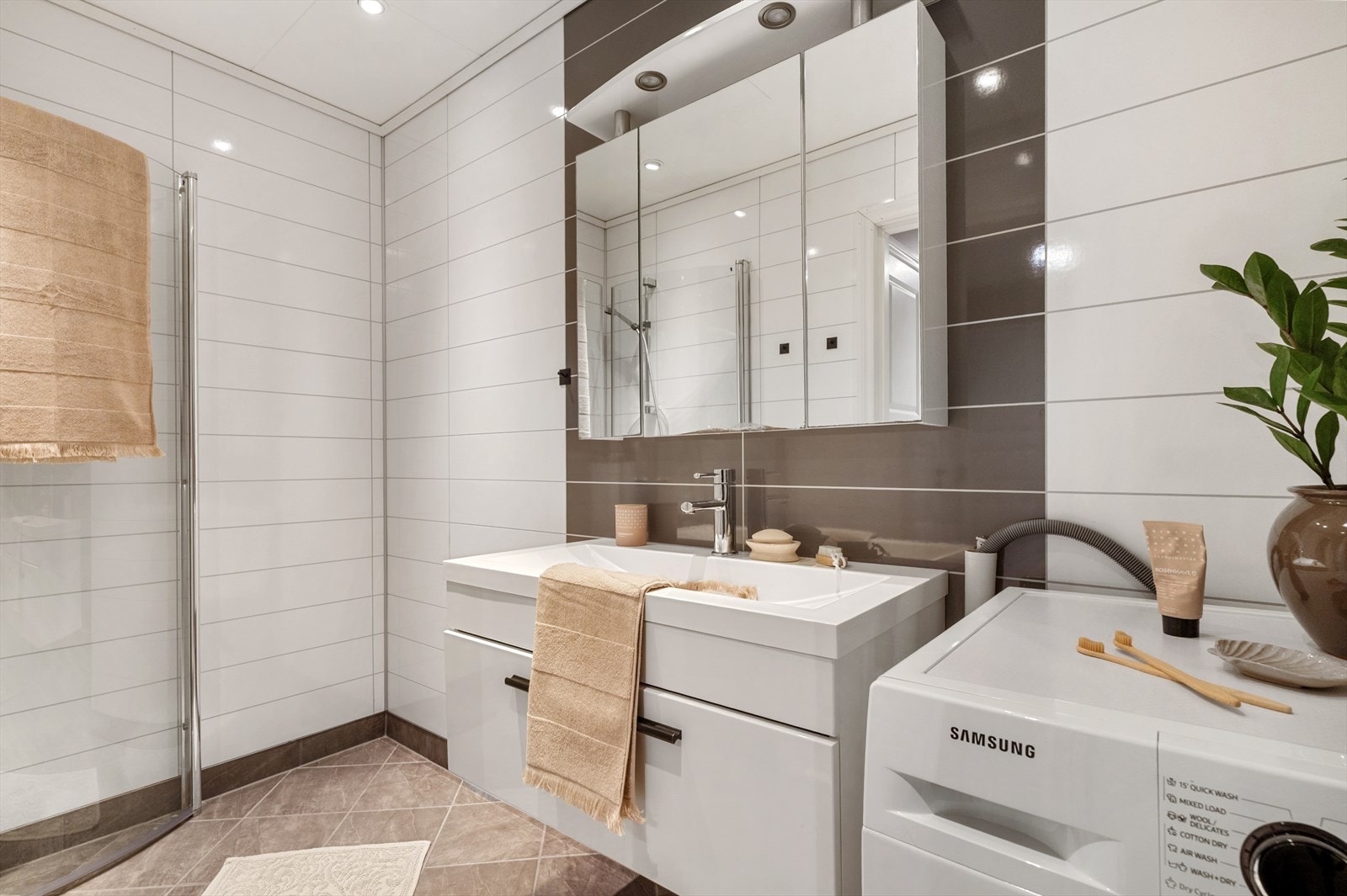 Badet er helfliset og er innredet med benkeskap med servant, dusjdører og opplegg for vaskemaskin. Galleribilde