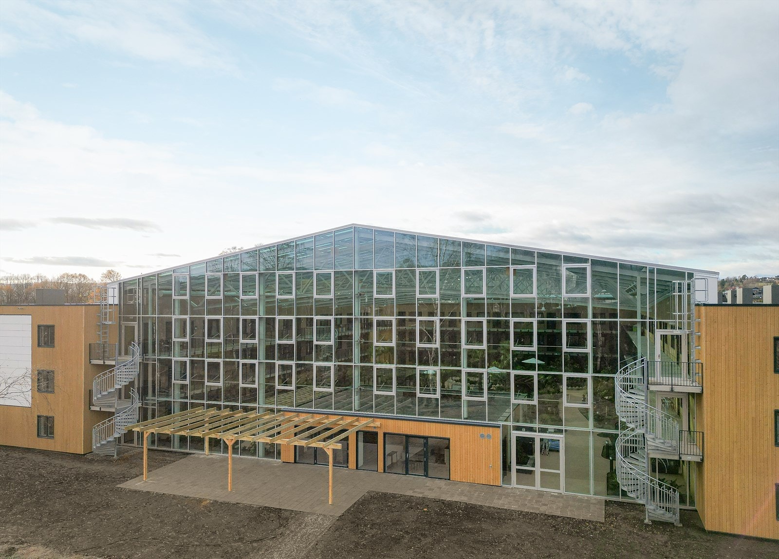 Flott glassfasade mot øst. Felles, stort uteområde i forkant av vinterhagen. Markterrasse belagt med betongstein Galleribilde