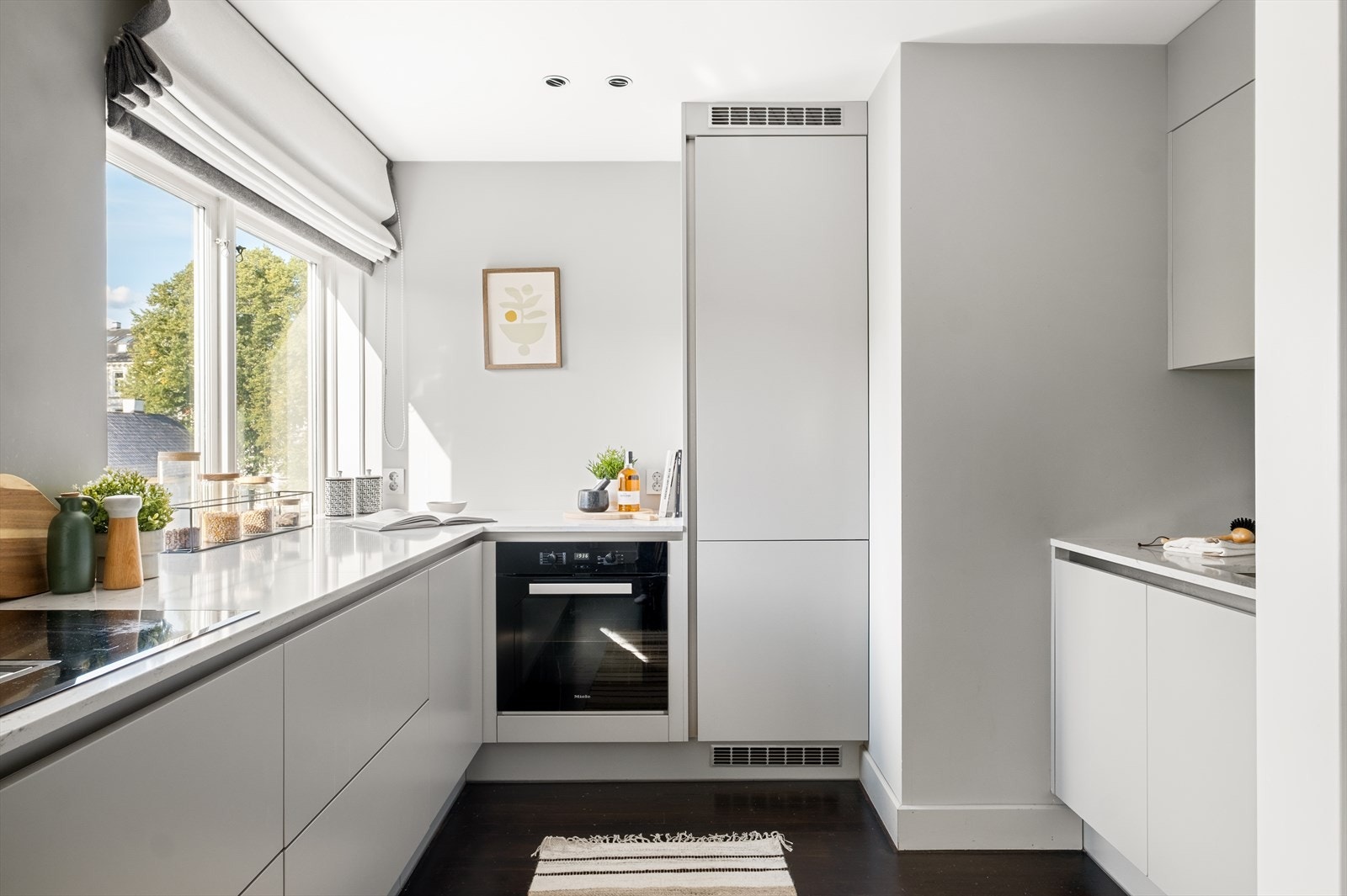 Moderne kjøkkeninnredning med glatte fronter, benkeplate av stein, med nedfelt vaskekum og overskap over vaskekummen. Galleribilde