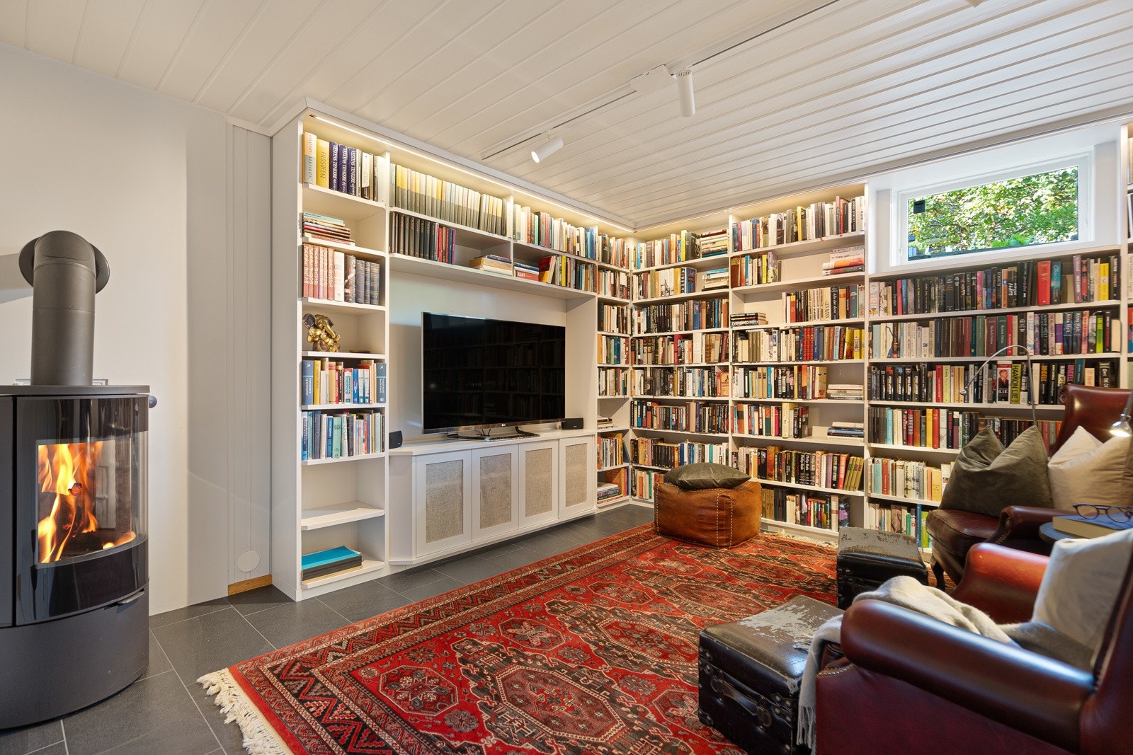 Stuen i underetasje er pusset opp med nye fliser, peisovn og plassbygde bokhyller Galleribilde