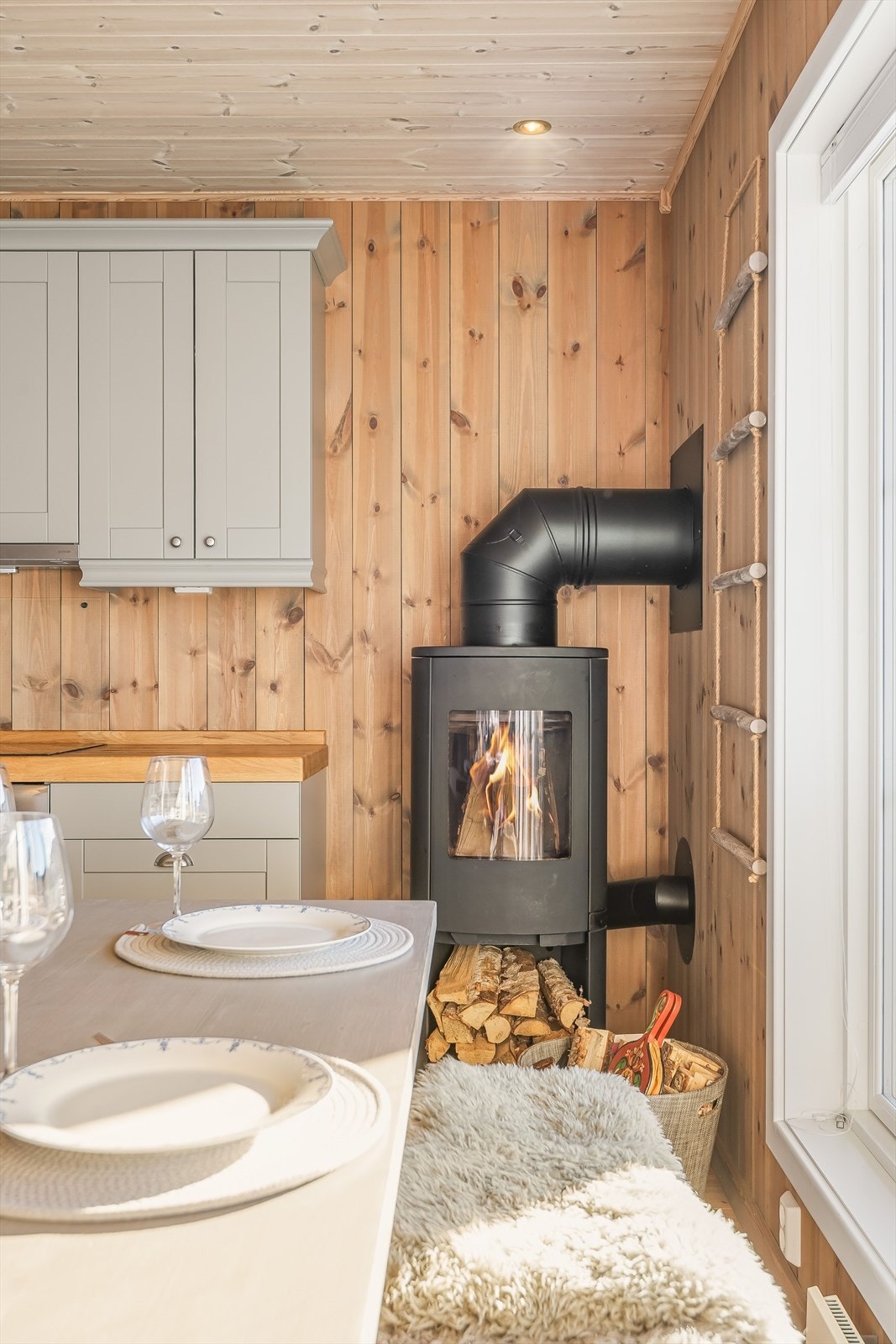 I hjørnet av rommet er det en moderne vedovn som både gir god varme og bidrar til ekstra hygge. Galleribilde