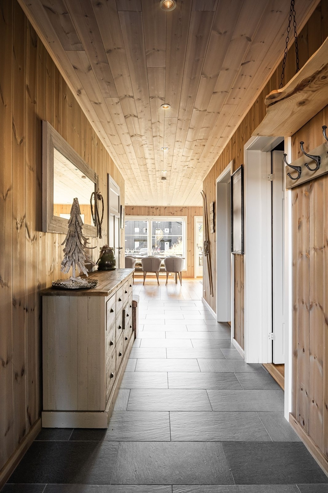 Entréen har god standard med mørke fliser på gulv, elektrisk gulvvarme, lun panel på veggene, skjult elektrisk anlegg og downlights i himlingen. Galleribilde