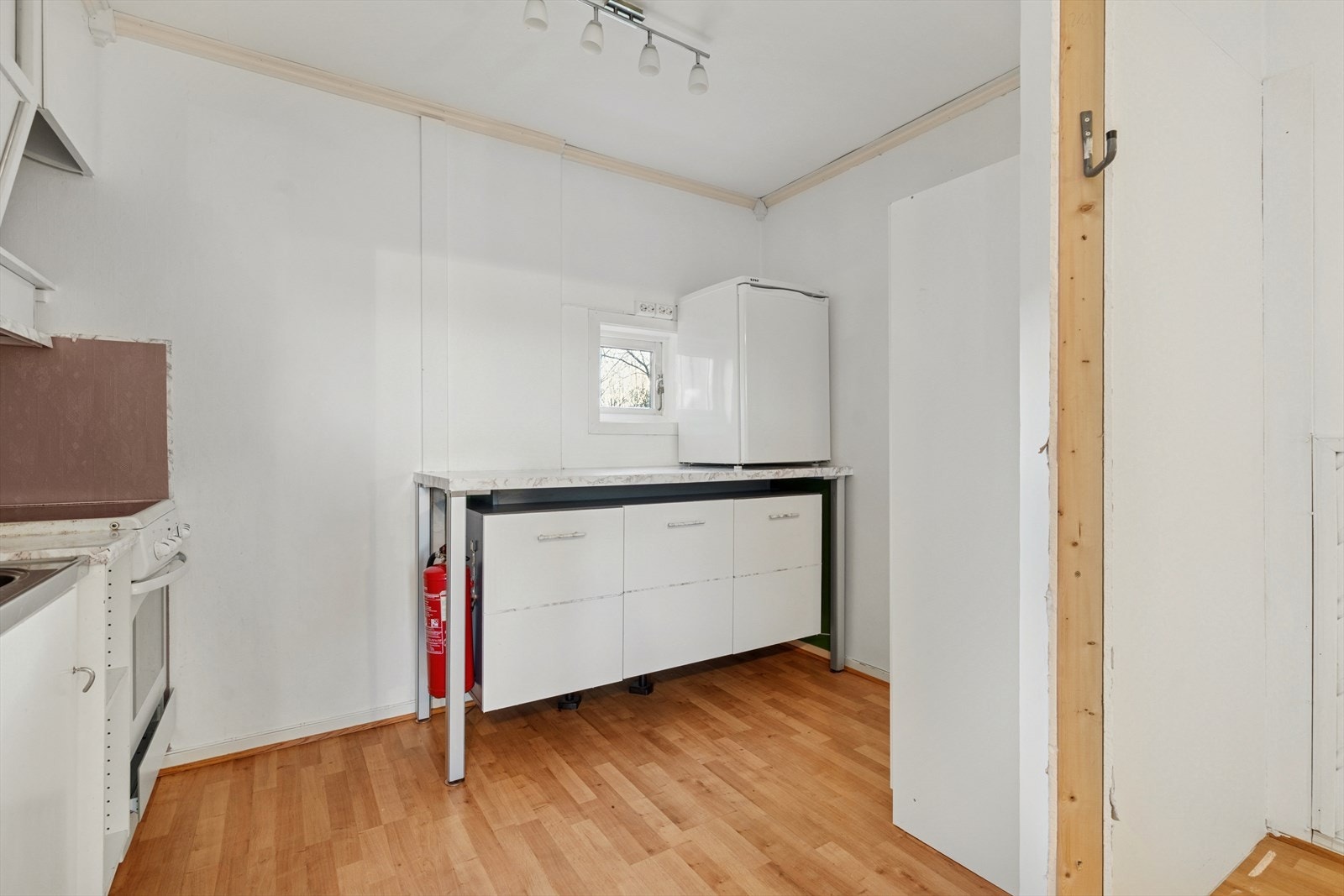 Kjøkkenet har en eldre innredning som er moden for utskifting - Innredningen har malte slette fronter, laminert benkeplate og stålvask med benkebeslag Galleribilde