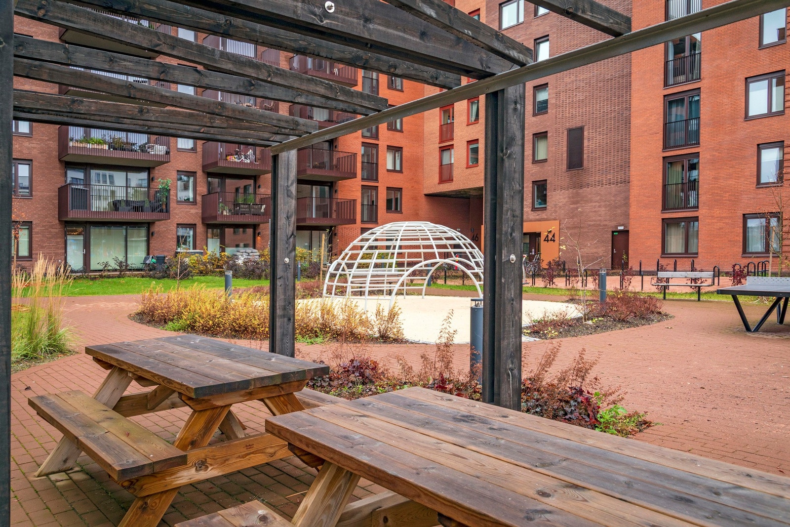 Gårdsrommet er opparbeidet med pergola, sittebenker, lekeapparater og beplantning. Galleribilde