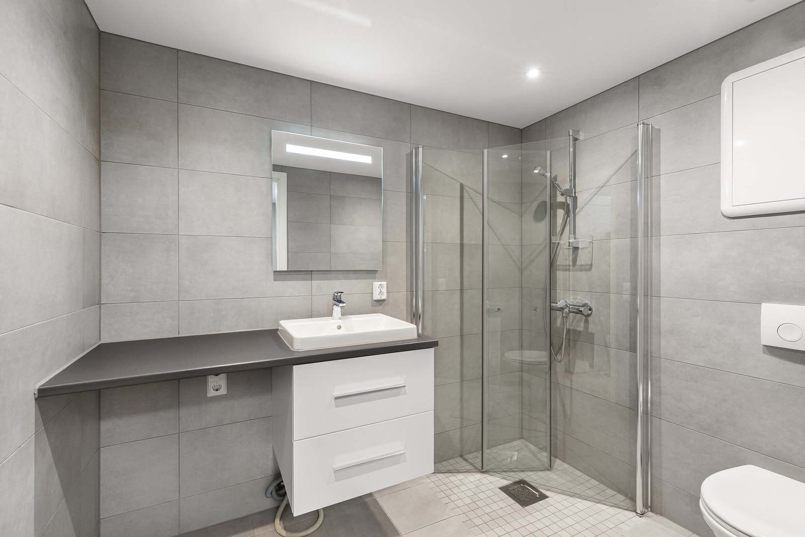 Delikat og pent flislagt bad med varme i gulv og opplegg for vaskemaskin. Galleribilde