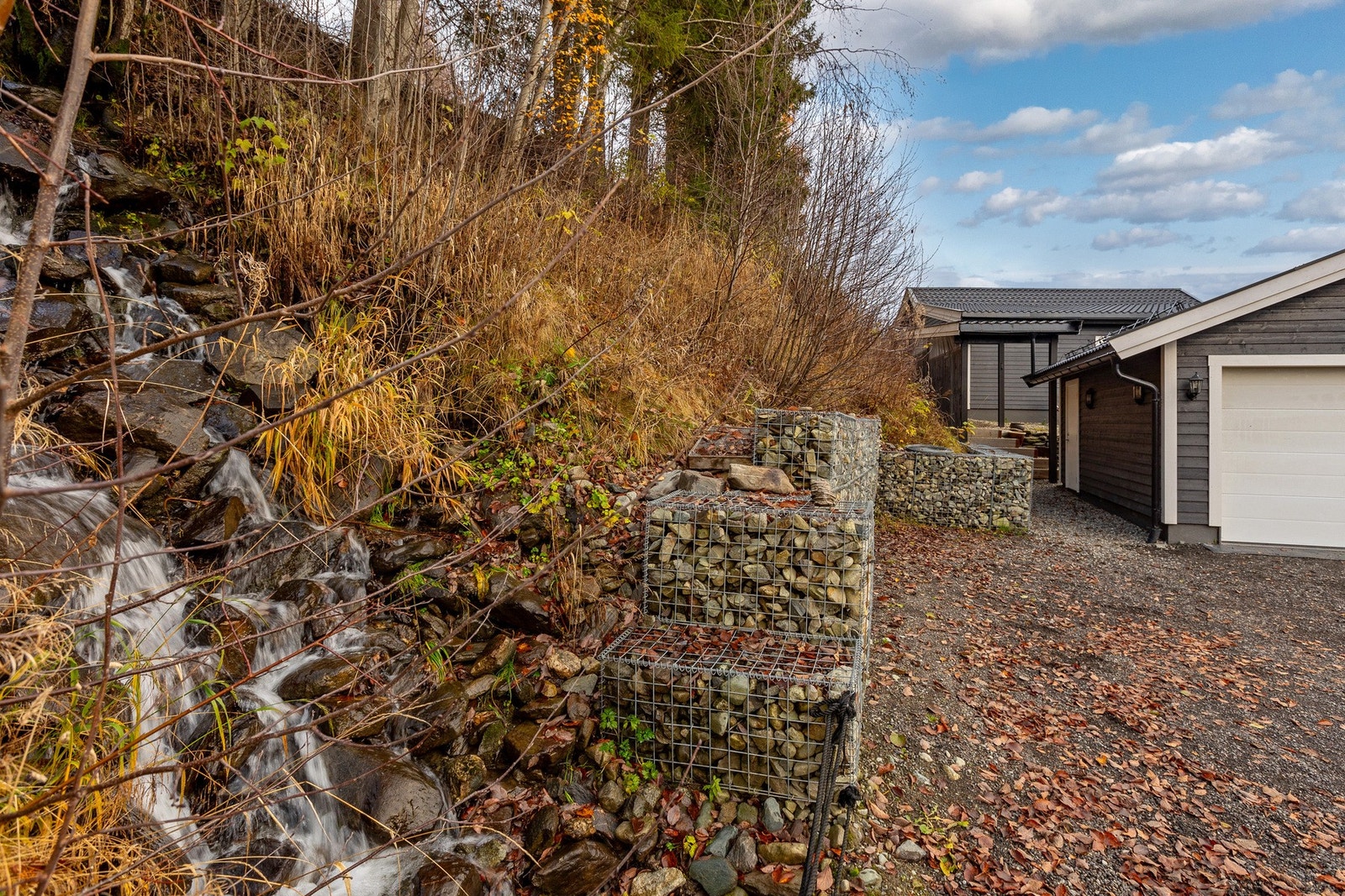 Tomten er pent opparbeidet med gruset innkjørsel, solide støttemurer i naturstein og gode parkeringsmuligheter foran garasjen. Galleribilde