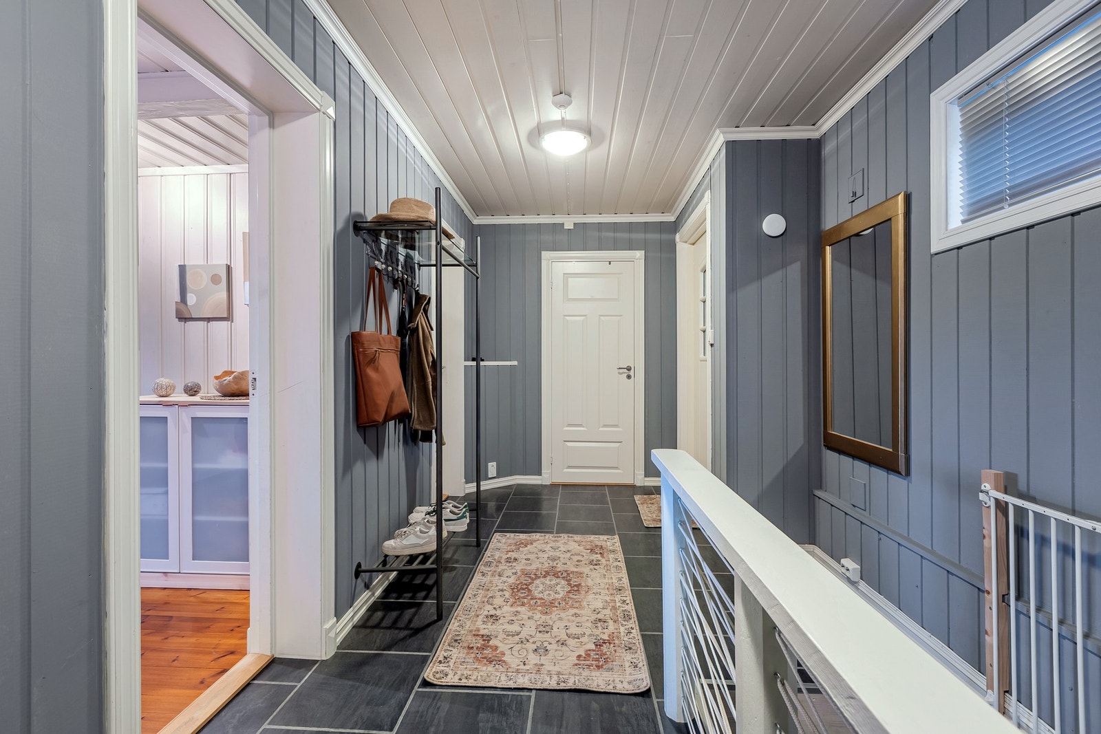 Fra gangen er det trapp ned til kjelleretasjen, som gir enkel adkomst til boligens øvrige bruksarealer. Den hvitmalte trappen har rekkverk med spiler. Galleribilde