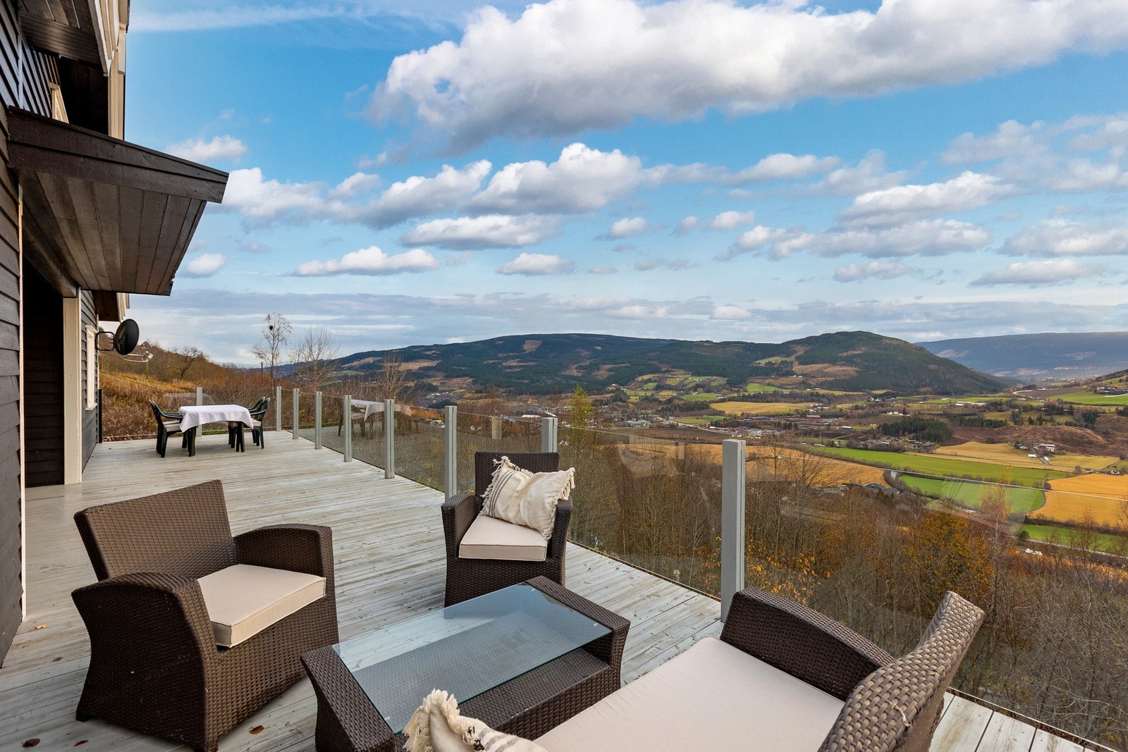 Den romslige verandaen er bygget i solid treverk og med et stilrent glassrekkverk som gir et moderne uttrykk. Galleribilde