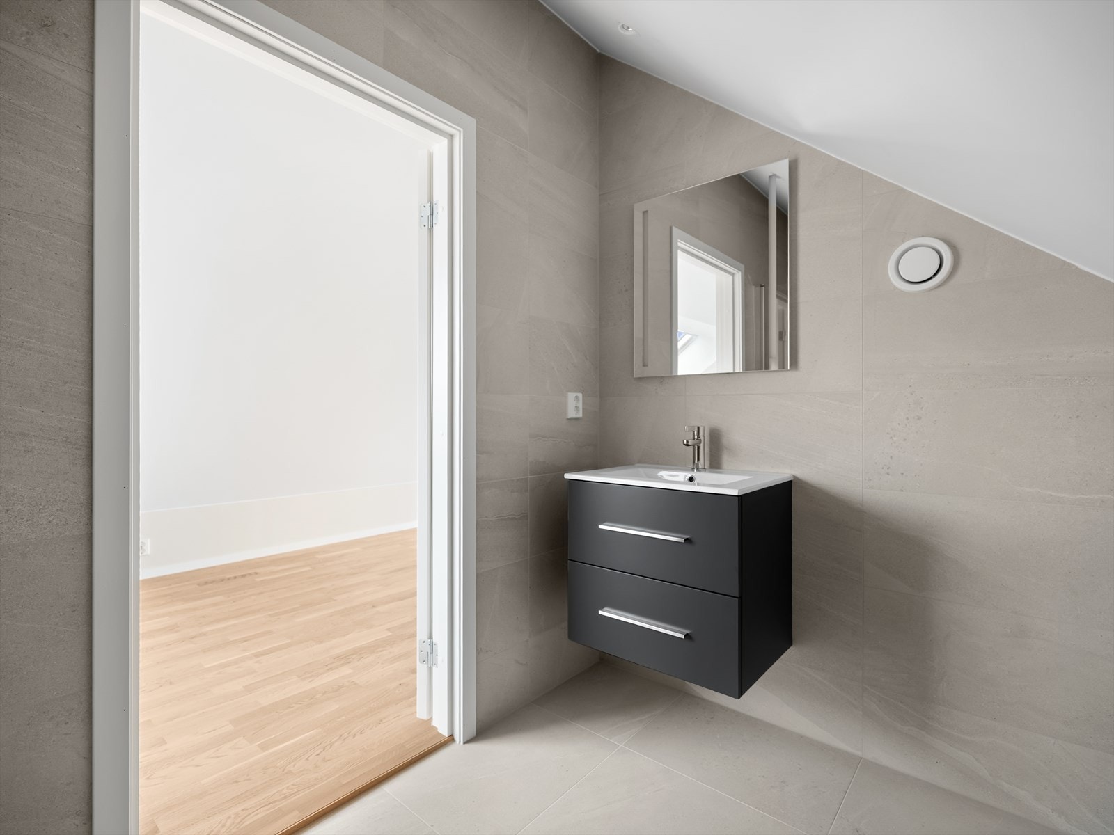 Praktisk bad som er innredet med vegghengt toalett, dusjhjørne med innfellbare dører og baderomsinnredning med skuffer, servant og speil. Galleribilde