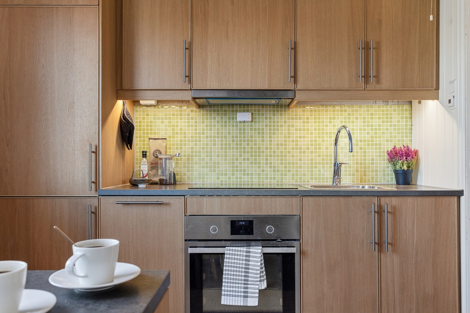 Pent kjøkken fra 2018 med integrerte hvitevarer som kjøleskap med fryser, komfyr, oppvaskmaskin og indukjsonstopp. Galleribilde