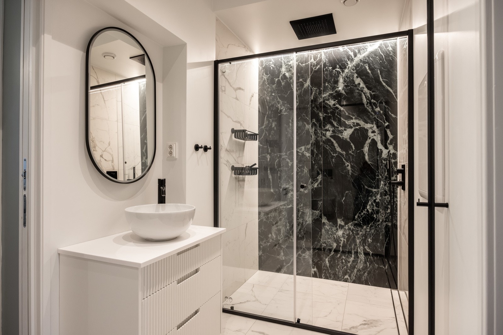 Bad ll - Et lekkert flislagt baderom fra 2023 med varmekabler i gulv. Den romslige dusjsonen har en takmontert regndusj, kombinert med elegante glassvegger i herdet glass. Galleribilde