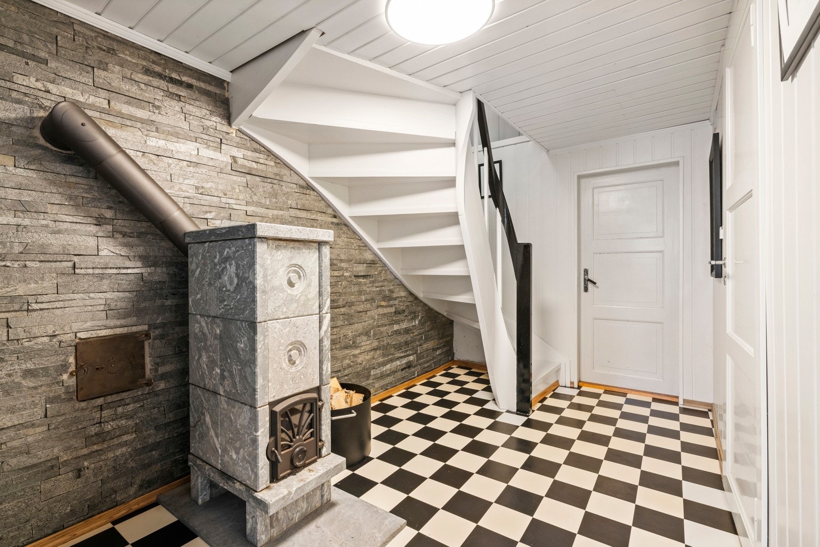 Trappegang. Rommet har en klebersteinsovn for oppvarming. I kjelleren er det også et vaskerom og tørkerom. Galleribilde