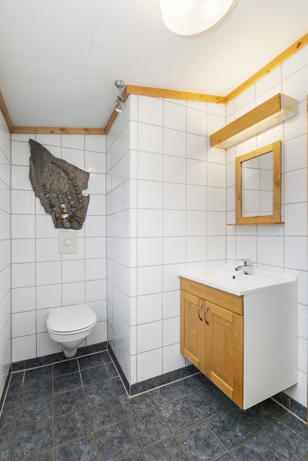 Flott flislagt bad med vegghengt toalett, servant og dusj Galleribilde