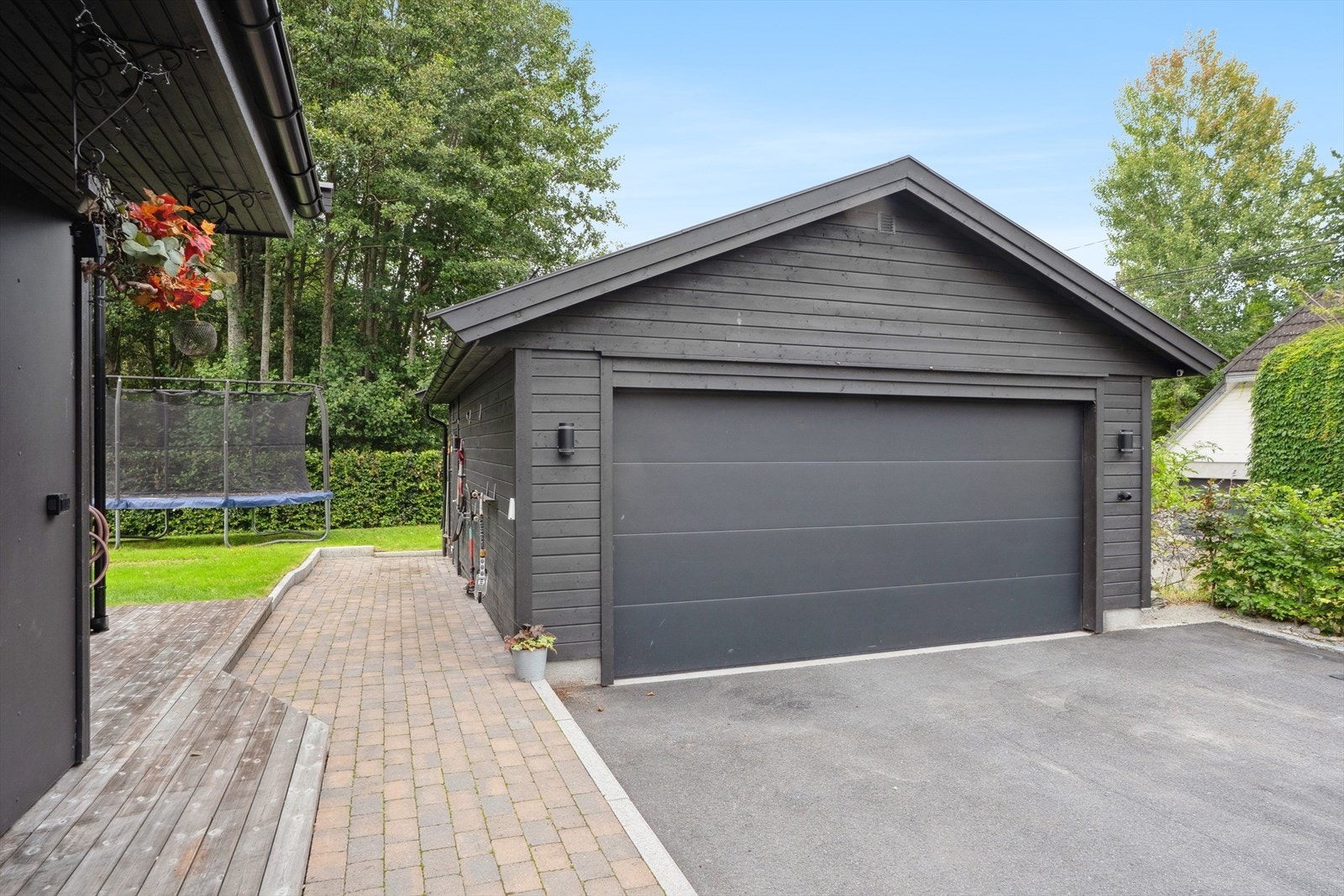 Tomten er tilrettelagt med asfaltert gårdsrom, steinbelagte områder, platting/gangsti, plen og variert beplantning. Galleribilde