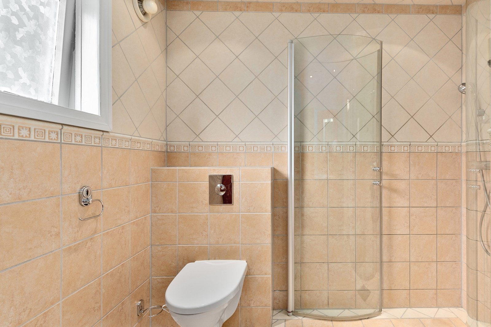 Badet er utstyrt med dusjnisje med glassdører, vegghengt toalett og baderomsinnredning med servant. Galleribilde