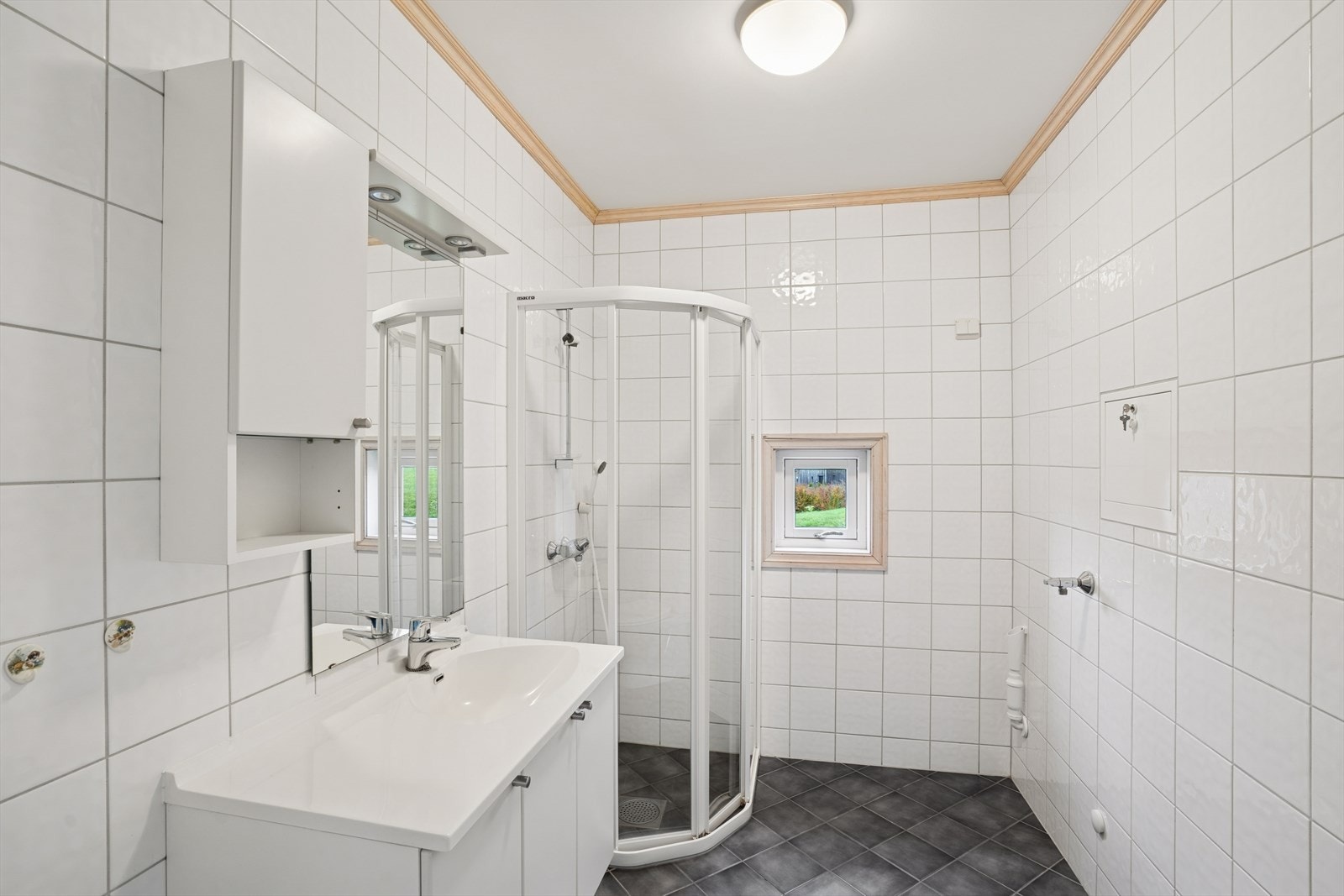 Pent flislagt bad med varmekabel. Hvite tidløse fliser på vegger og grå fliser på gulvet. Det er også et lite vindu for ekstra utlufting. Galleribilde