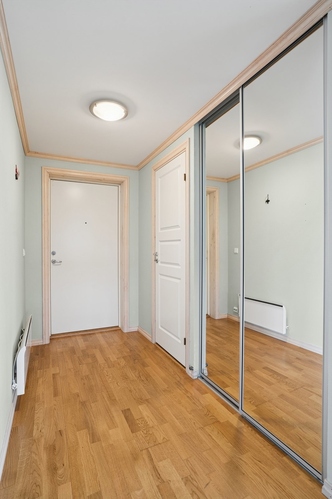 Fra fellesgang har man adkomst til boligens entré. Entreen er praktisk utstyrt med skyvedørsgarderobe og porttelefon. Galleribilde