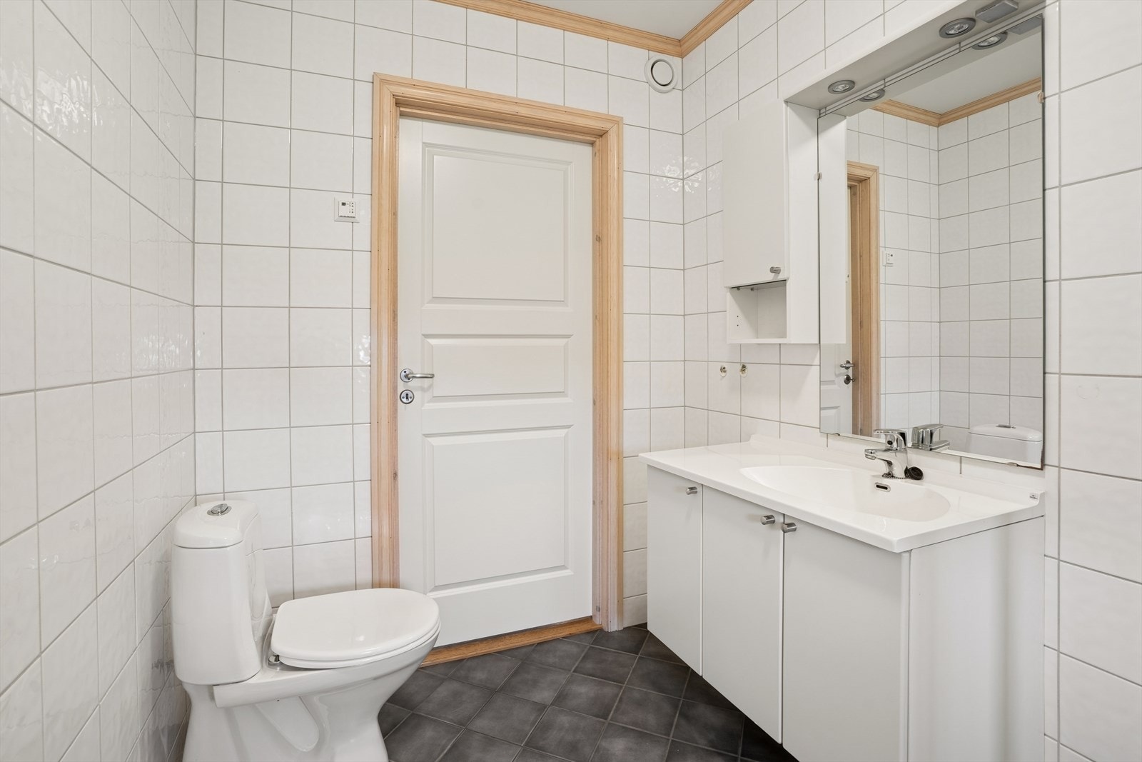 Badet er utstyrt med klosett, servant med underskap, speil og dusjhjørne med faste vegger. Opplegg for vaskemaskin. Galleribilde