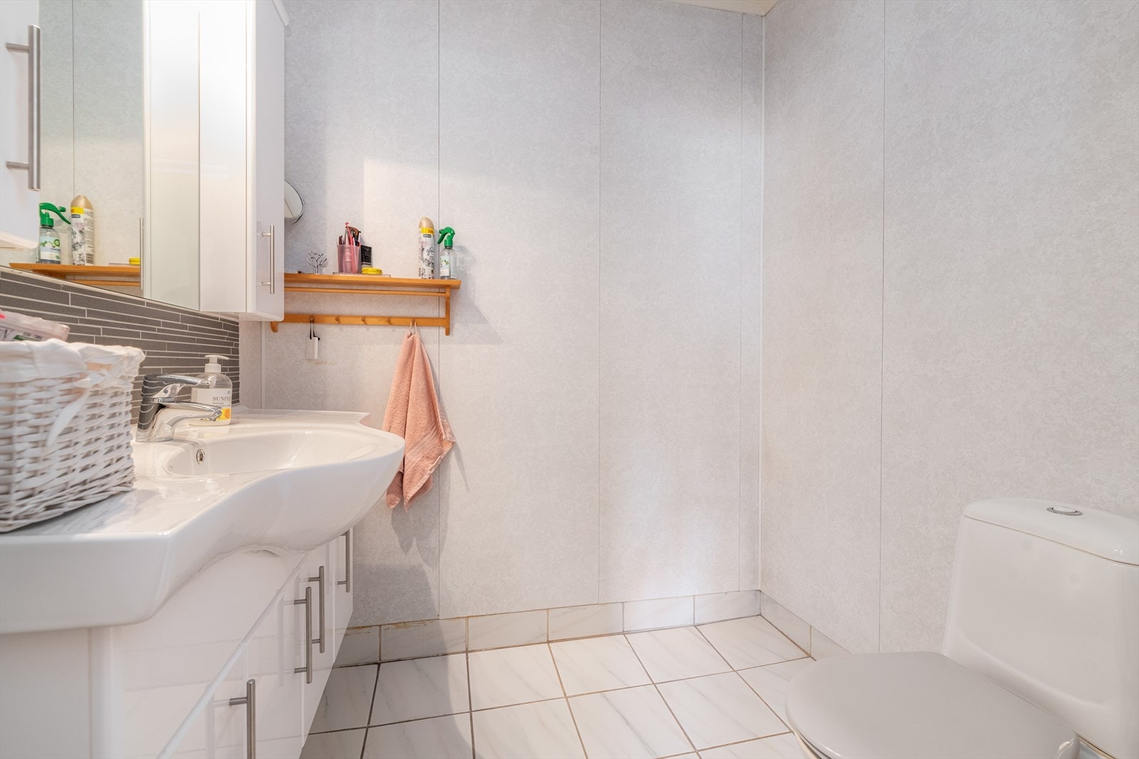 Toalettrommet innehar toalett og servantinnredning med skap og speil. Galleribilde