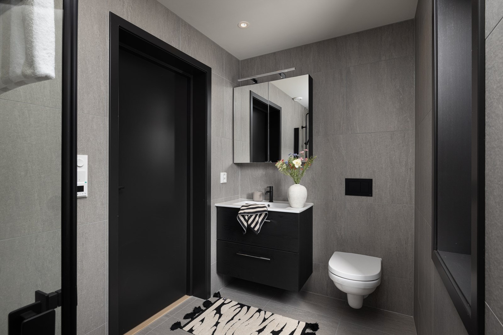 Stilrent bad med servant, vegghengt toalett, hjørnedusj og opplegg for vaskemaskin. Galleribilde