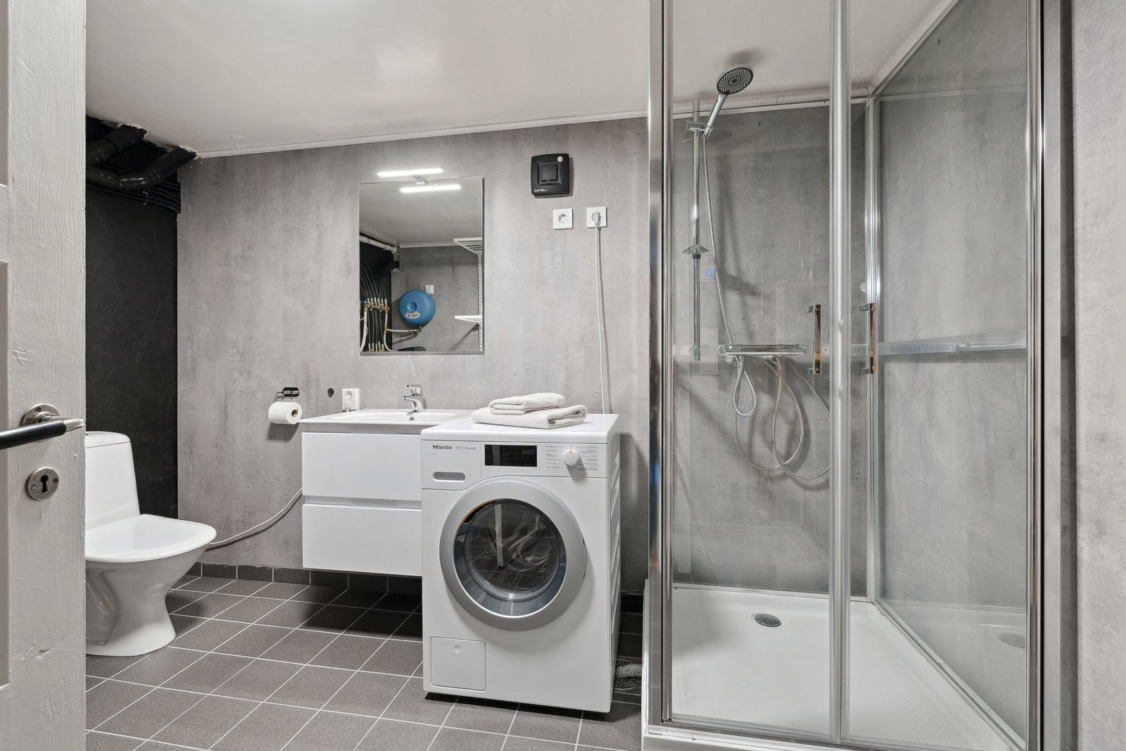 Bad/vaskerom i kjelleretasjen med hvit baderomsinnredning og romslig dusjkabinett. Vaskemaskinen medfølger ikke. Galleribilde