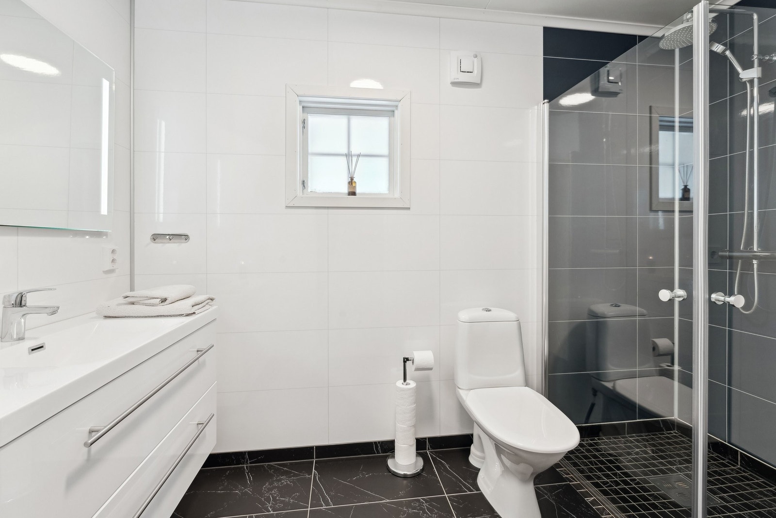 Bad i 1. etasje med dusjvegger og hvit baderomsinnredning Galleribilde