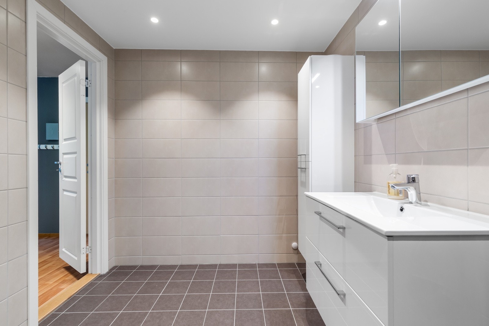 Badet er utstyrt med dusjhjørnet, servant med glatt utførelse og opplegg til vaskemaskin. Galleribilde