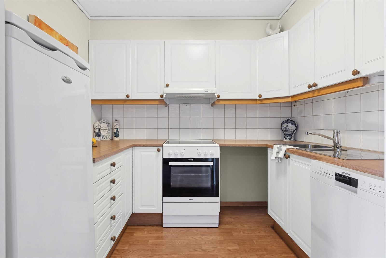 Kjøkkenet har innredning med profilerte fronter, fliser mellom over- og underskap, samt laminat benkeplate. Galleribilde