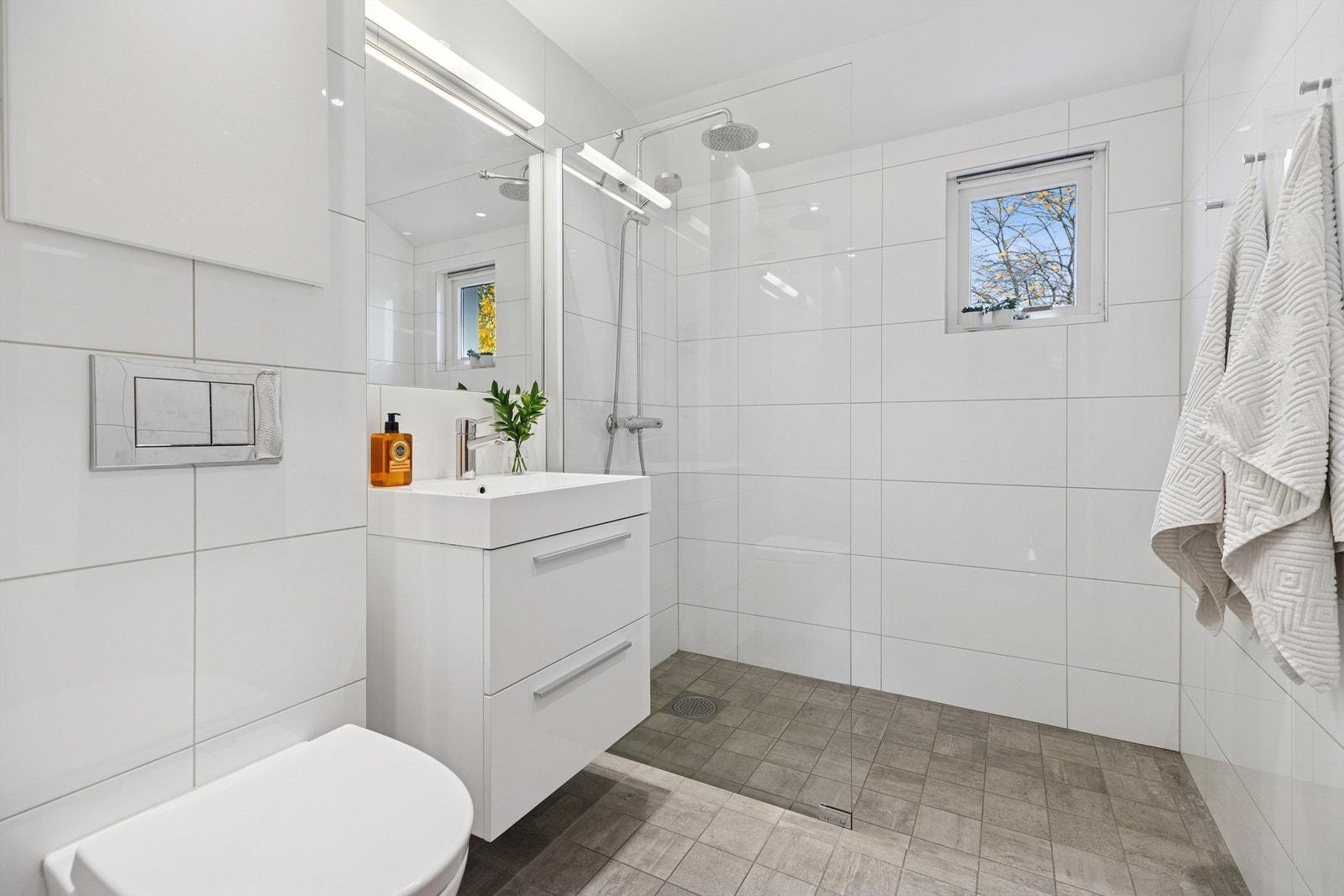 Klassisk, pent og flislagt baderom med gulvarme og et romslig dusjhjørne. Galleribilde