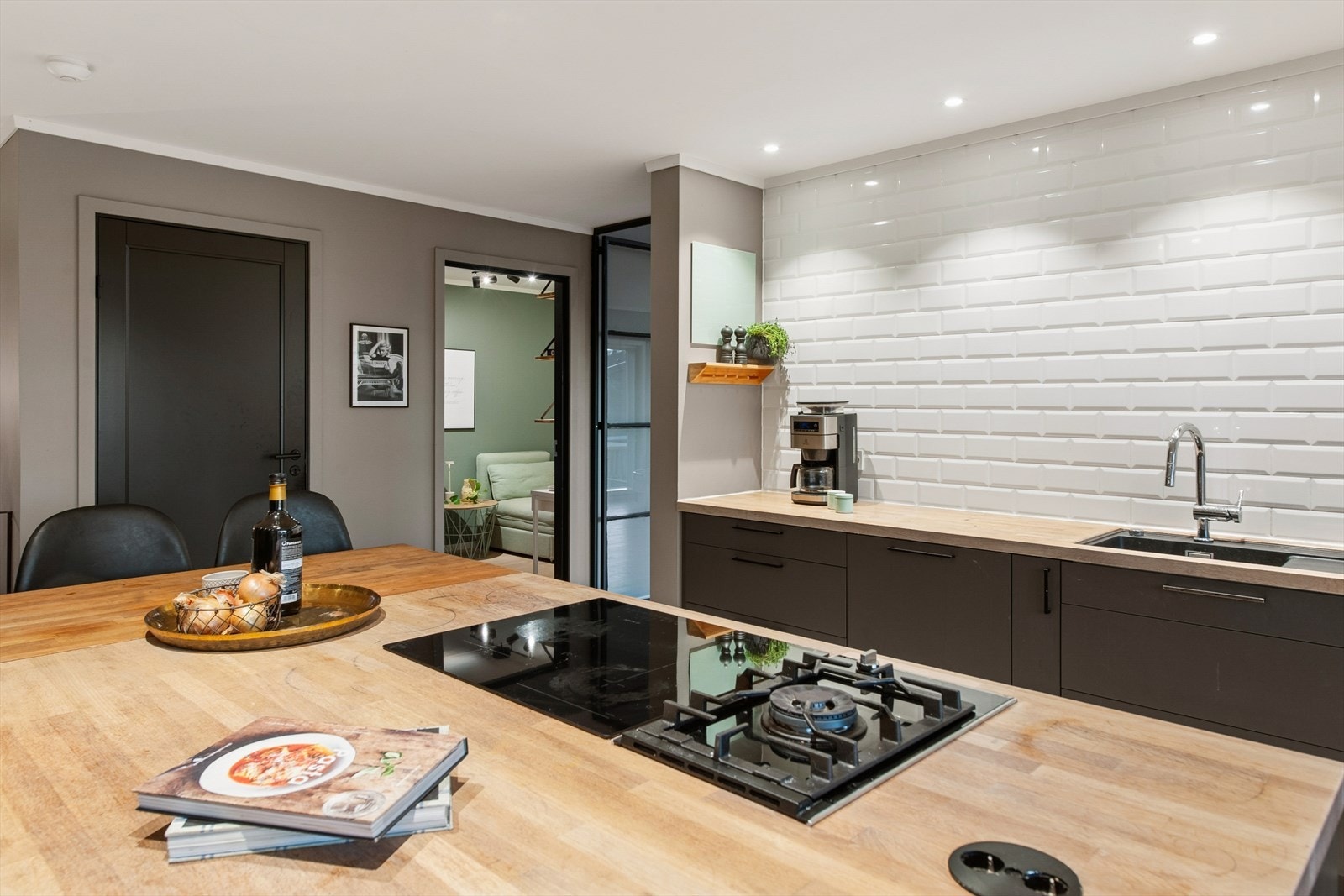 Kokeplass på kjøkkenøya, med gassbluss og platetopp med avtrekksvifte montert i taket over. Galleribilde