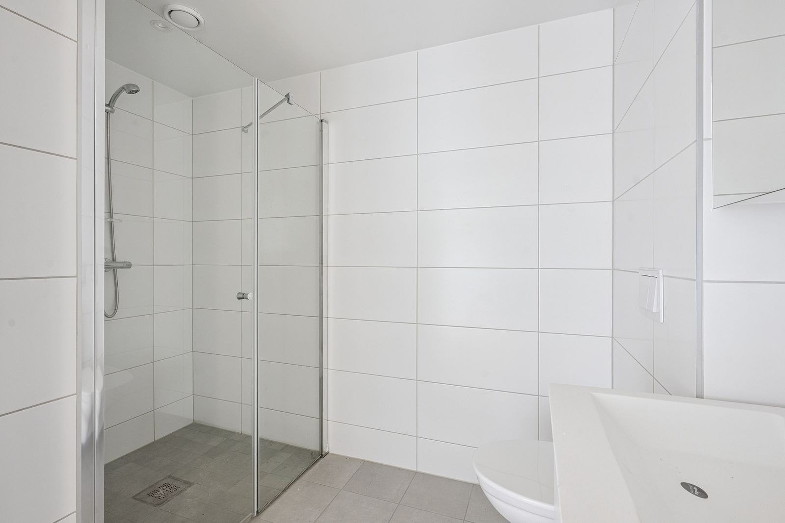 Flott flislagt bad med stort dusjhjørne og gode oppbevaringsmuligheter i servantskap Galleribilde