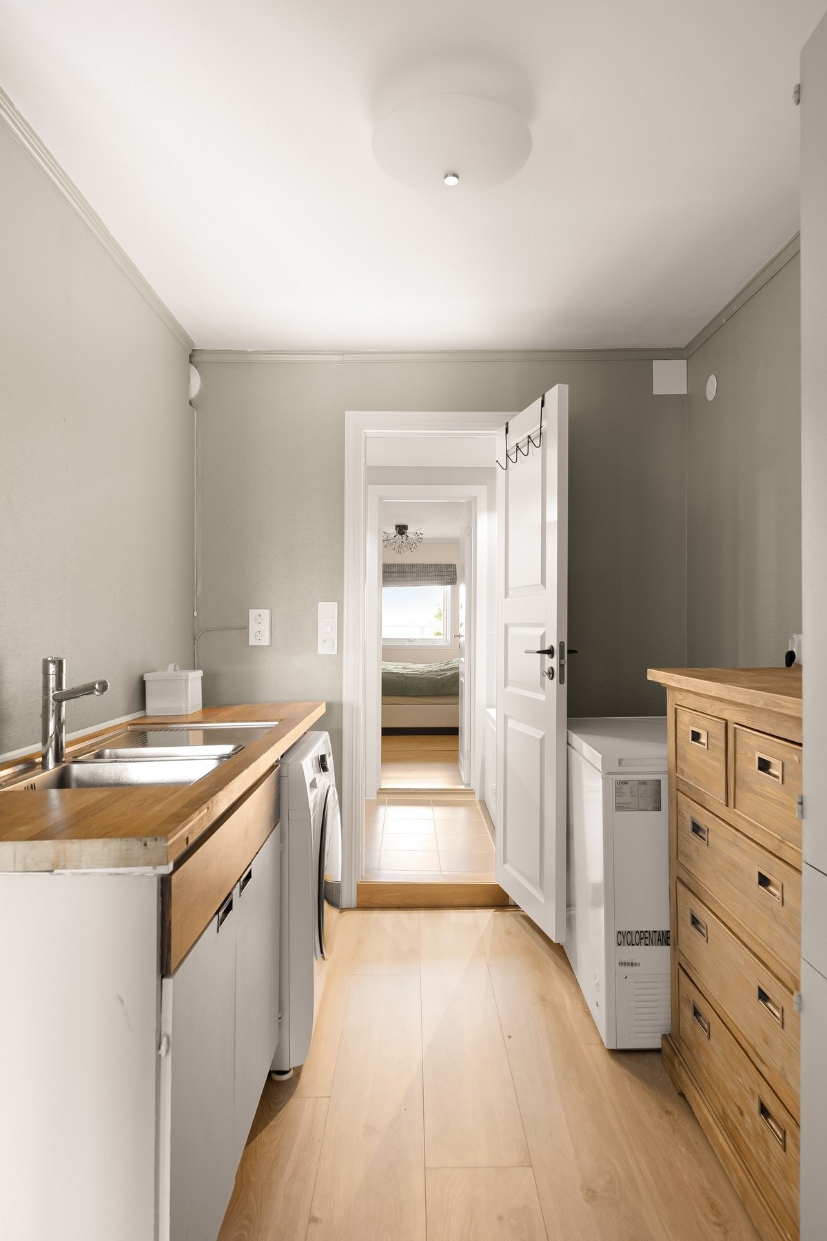 Praktisk vaskerom/grovkjøkken med benkeplass, vask og plass til maskiner. Galleribilde