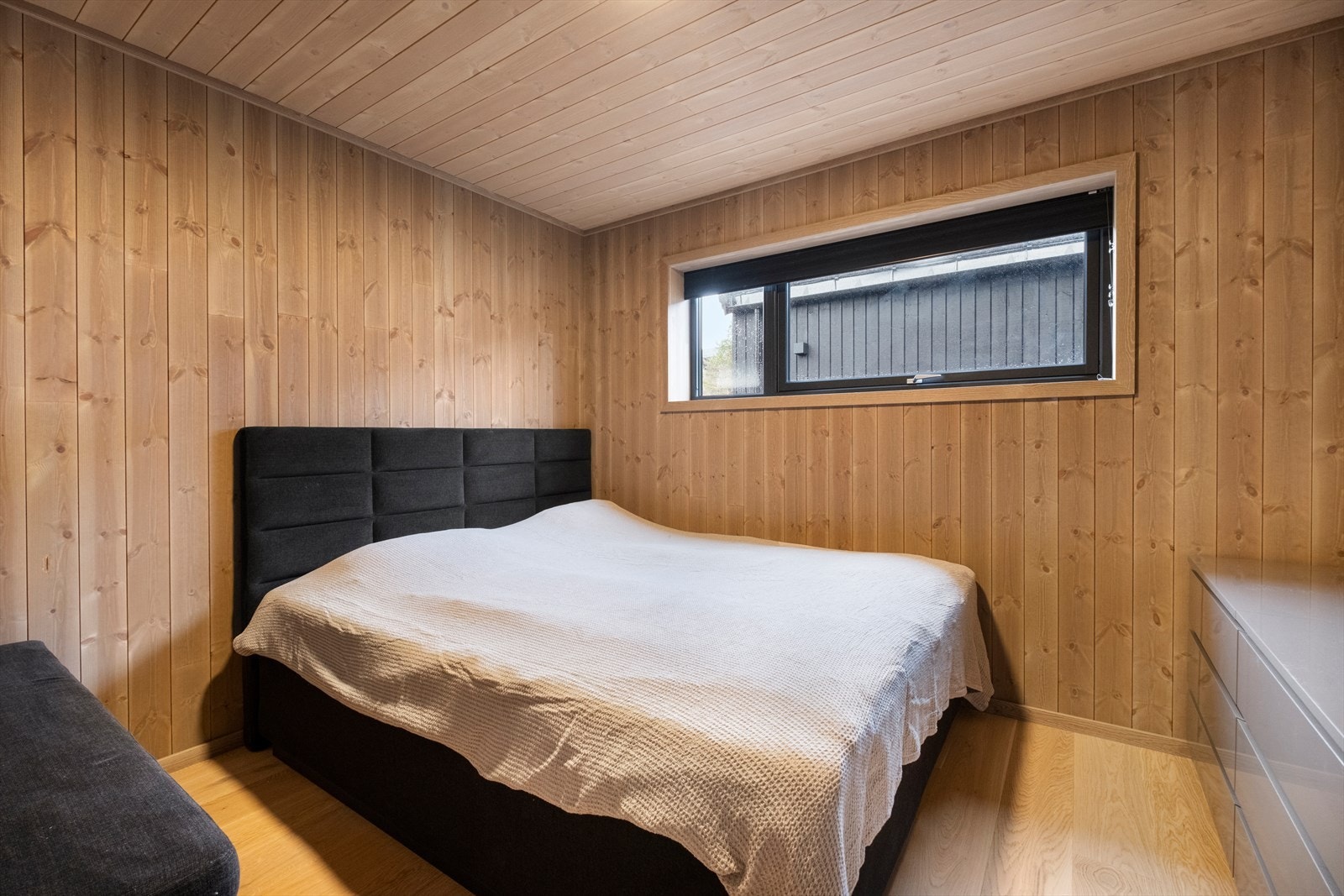 Panelvegger gir en varm og naturlig følelse i rommet, mens vinduet med energiglass sikrer god isolasjon. Galleribilde