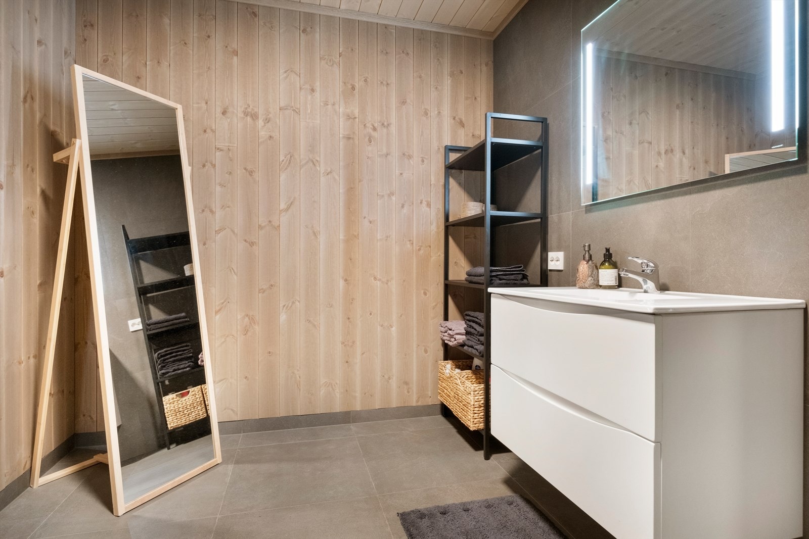 Panel på vegger gir et naturlig uttrykk, mens fliser på gulv sørger for enkel rengjøring. Galleribilde