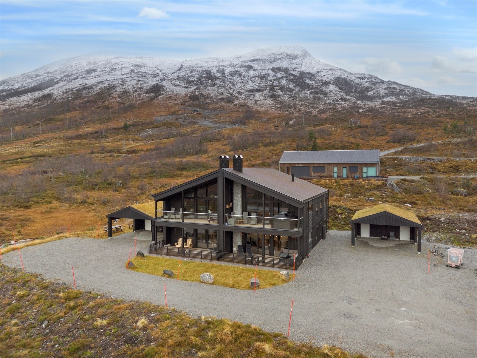 Fritidsboligen har en trekonstruksjon med stående og liggende bordkledning og terrasser med rekkverk av treverk. Galleribilde