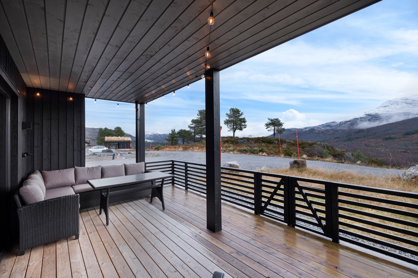 Utsikt fra terrassen viser fjellandskap og gruset innkjørsel. Galleribilde