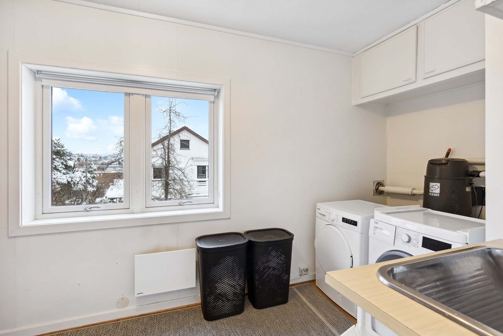 Romslig vaskerom med utslagsvask og opplegg til vaskemaskin. Det er installert sentralstøvsuger i boligen, og denne medfølger i handelen Galleribilde