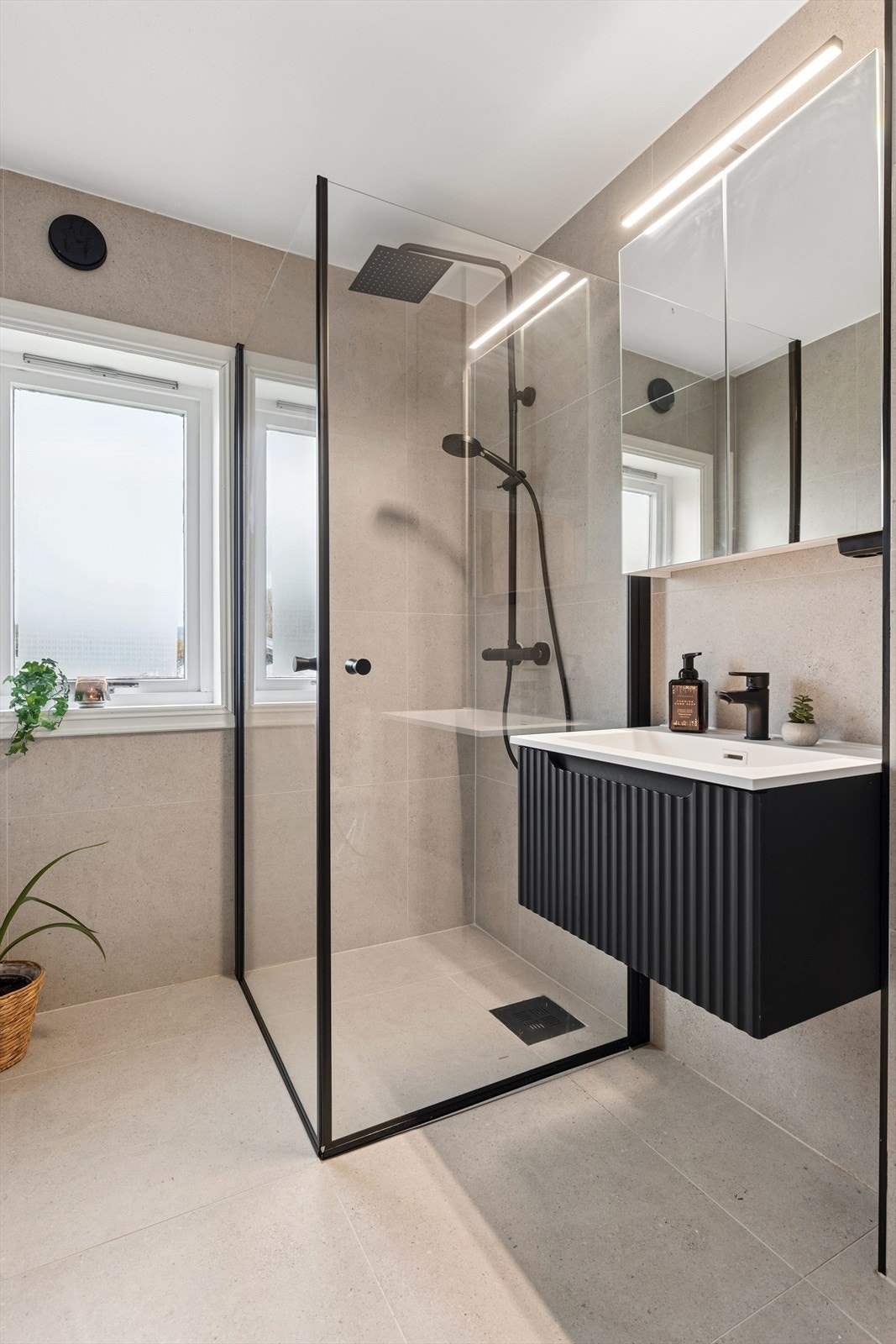 Baderommet er utstyrt med servantinnredning, oppbevaring i underskap, speilskap over servant og dusjnisje med foldbare dusjdører Galleribilde