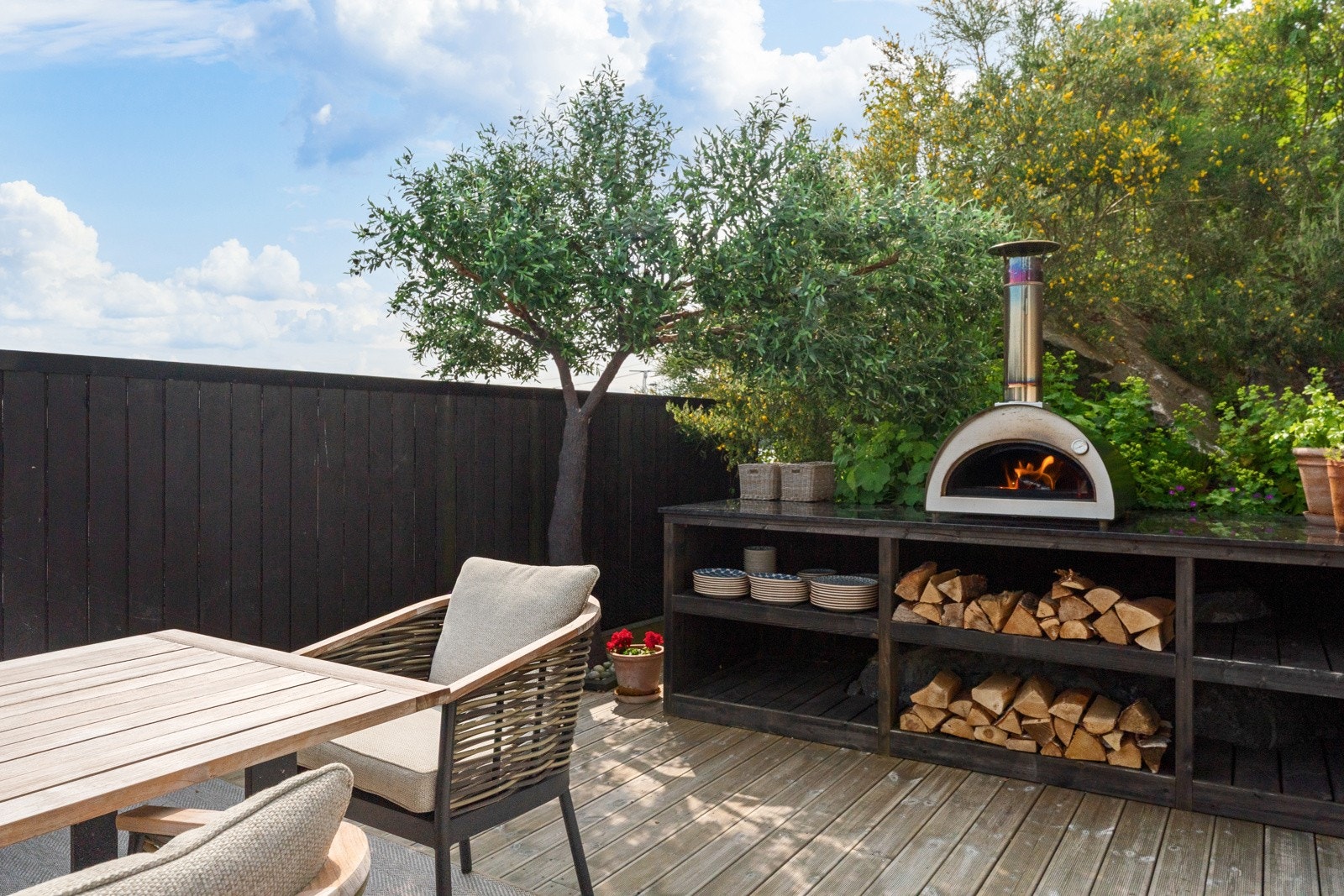 Utekjøkken med granitt benkeplate og pizzaovn setter "prikken over i-en" på hagen Galleribilde