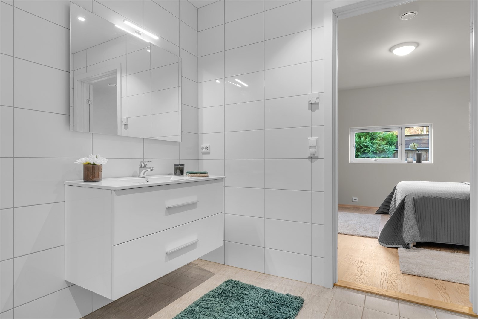 Badet i boligen er moderne og stilrent, med lyse fliser på både gulv og vegger som gir et eksklusivt og tidløst uttrykk. Galleribilde