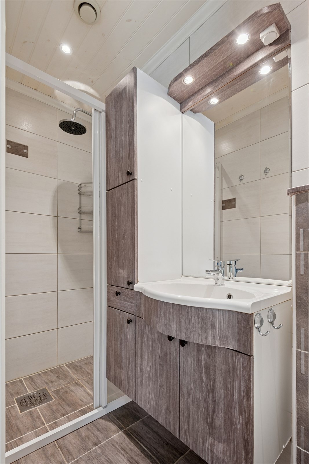 Badet i første etasje består av speil med belysning over, servant med seksjon, vegghengt toalett og dusjsone med garnityr og glassvegger. Galleribilde