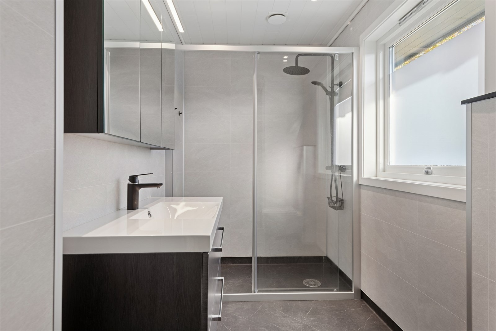 Bad i andre etasje består av speil med belysning over, servant med seksjon, vegghengt toalett og dusjsone med garnityr og glassvegger. Galleribilde