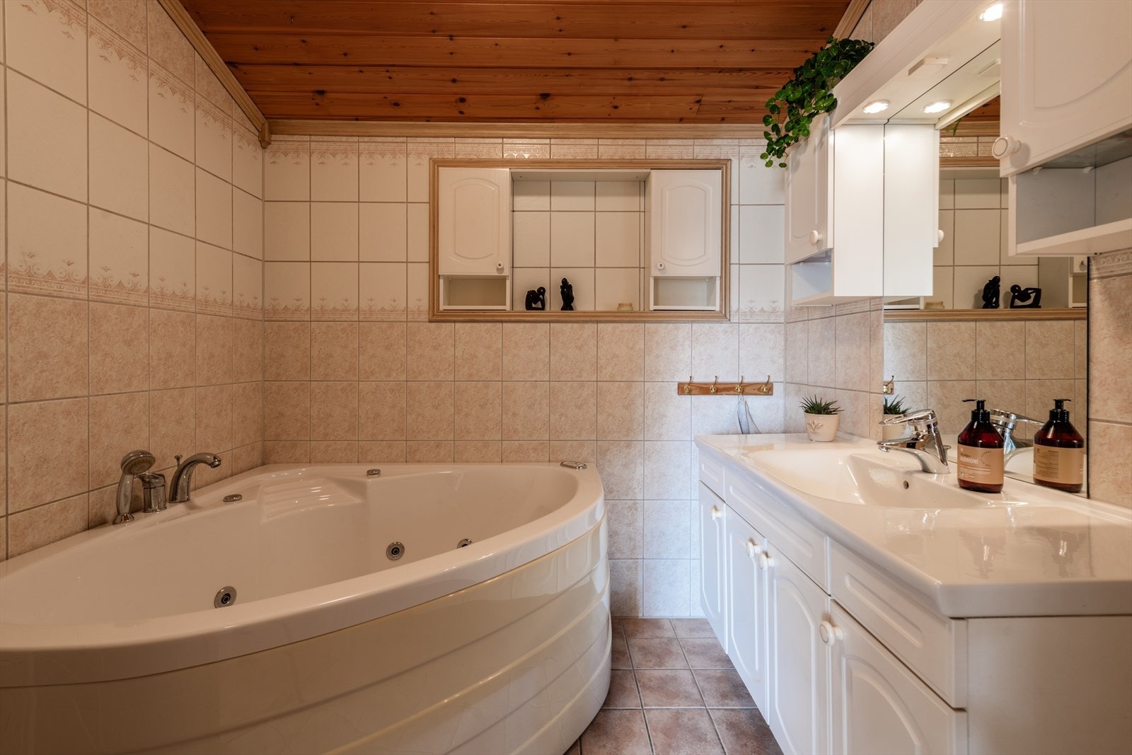 Bad: har fliser på gulv, det er fliser på vegger og det er trepanel i himling. Badet har servantinnredning, håndvask og boblebad Galleribilde