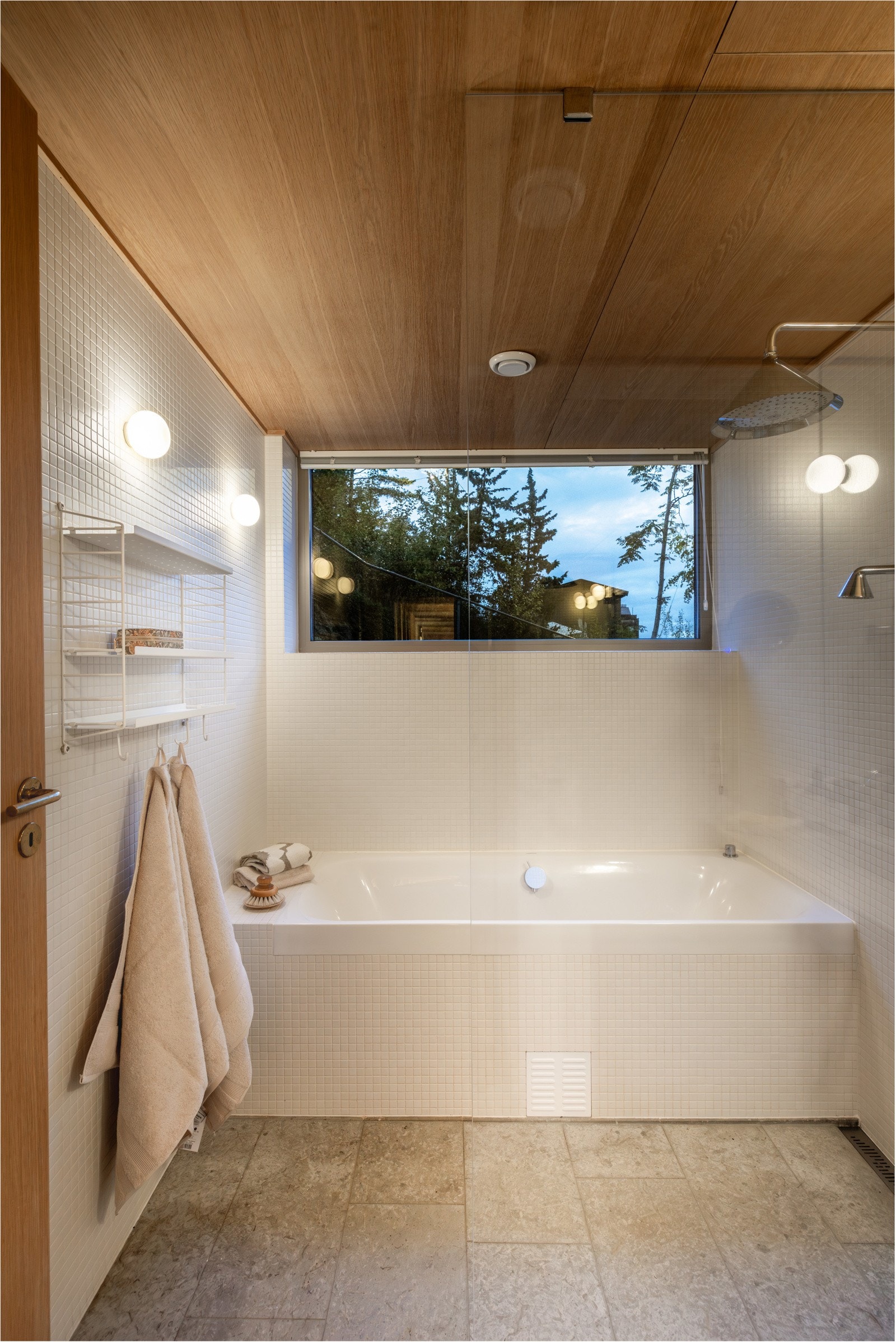 Et lyst og moderne baderom med flislagte vegger og tak i eikefiner som gir en varm og elegant atmosfære.